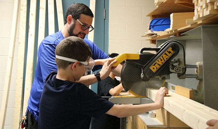 Photo of Teacher and Student in Woodworking Class using a saw