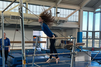 student gymnast on uneven parallel bars