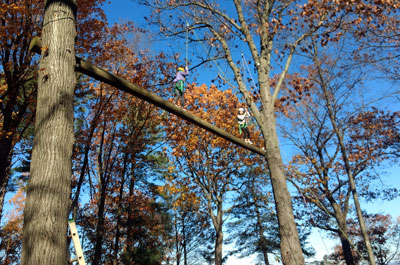 two students on very high ropes element attached to wires and harnesses