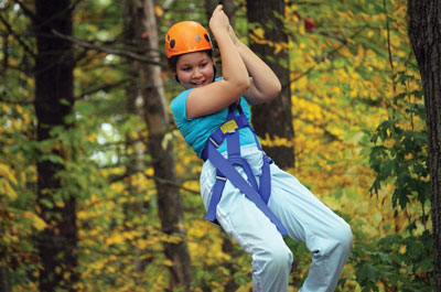 Girl in harness being lowered from high ropes course