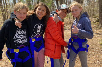 four middle school students in harnesses on ropes course