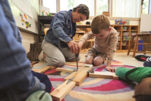 kindergarten student and teacher using tools in STEM class