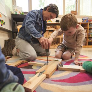 kindergarten student and teacher using tools in STEM class