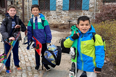 Three skiers with gear waiting for ski bus