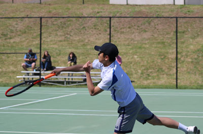 boy finishing tennis serve