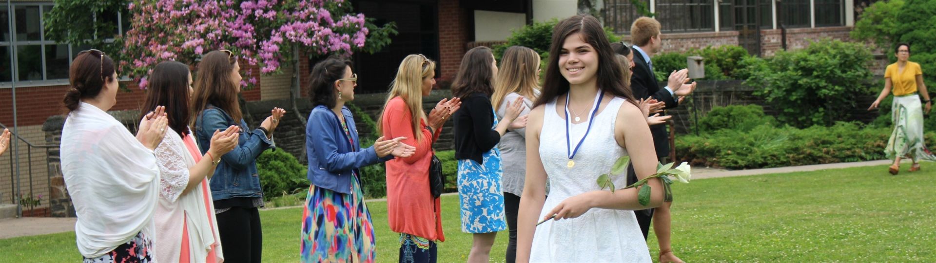 Girl in white dress holding a rose processing in for graduation