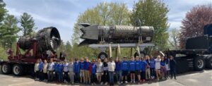 Grade 2 students standing in front of large Pratt & Whitney engine