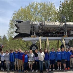 Grade 2 students standing in front of large Pratt & Whitney engine