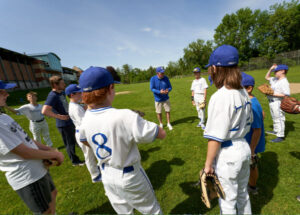 Middle school baseball players in a circle listening to the coach