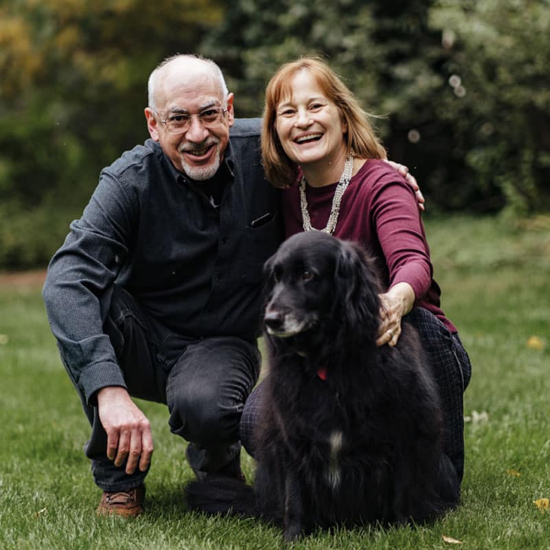 Couple posing in grass with their dog