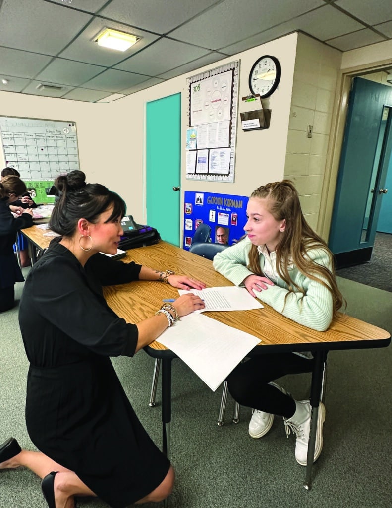 teacher working individually with a student on writing