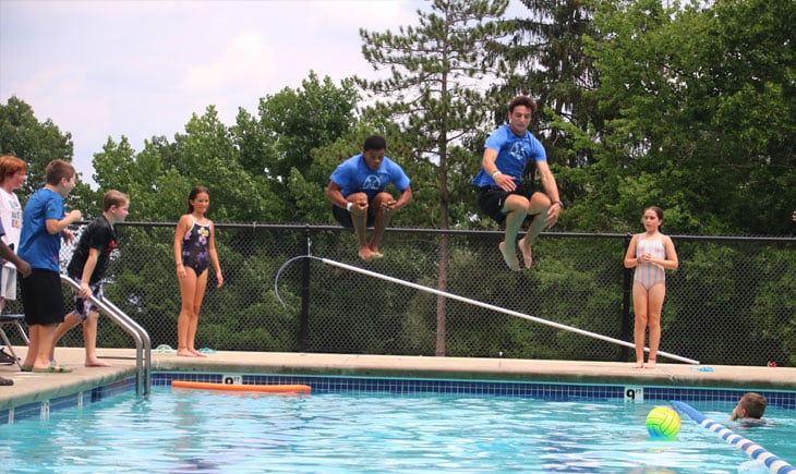 two male teens doing cannon ball into pool