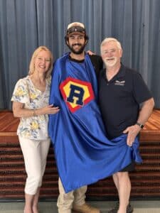 Aidan Guzman receiving award and superhero cape