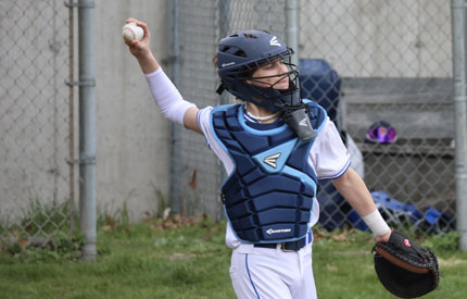 male middle school baseball catcher throwing ball