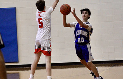 male basketball player shooting the ball with opposing defender in front of him attempting to block