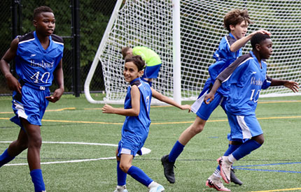 4 middle school soccer players celebrating a goal