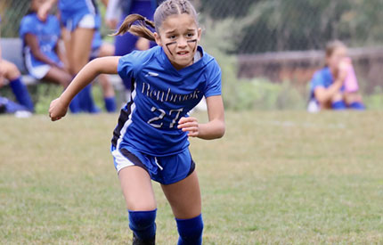 young girl running hard in soccer game