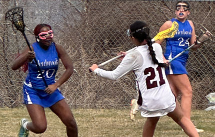 three middle school girls engaged in a lacrosse game