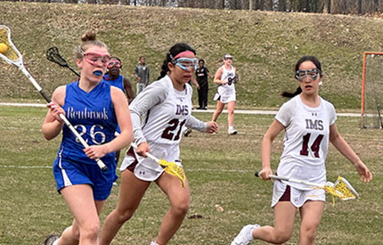 3 female lacrosse players with one cradling the ball