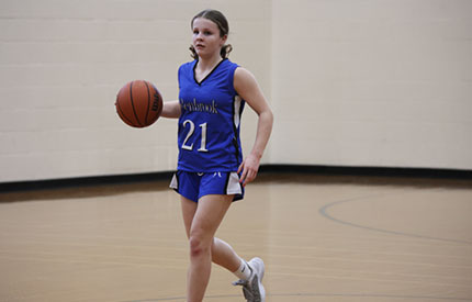 single female basketball player dribbling ball up court