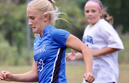 blond female with facial grimace working hard in soccer game