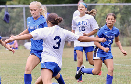 five middle school girls engaged in a soccer game