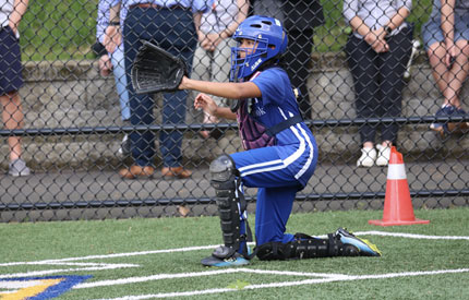 female softball catcher with glove out awaiting throw