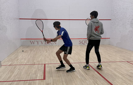 2 boys engaged in a game of squash