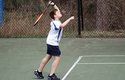 teenage boy serving a tennis ball