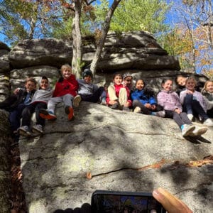 Group of students sitting on highly elevated rocks after climbing during their outdoor education trip