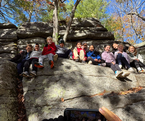 Group of students sitting on highly elevated rocks after climbing during their outdoor education trip