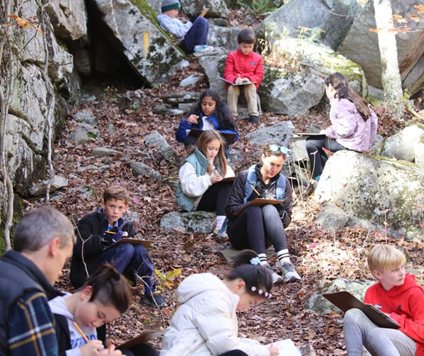 Third grade students doing a writing exercise in the woods