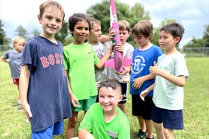 7 boys in a group with the rocket they built during rocketry at summer camp