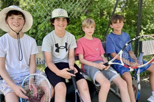 4 boys on a bench with tennis rackets