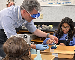 Middle school science teacher assisting students with an experiment