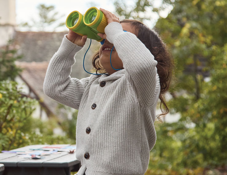 young boy peering through binocular curiously exploring the environment