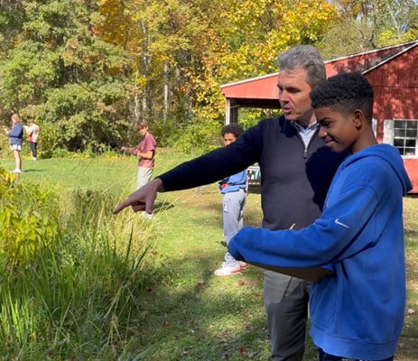 science teacher pointing out items to student pondside