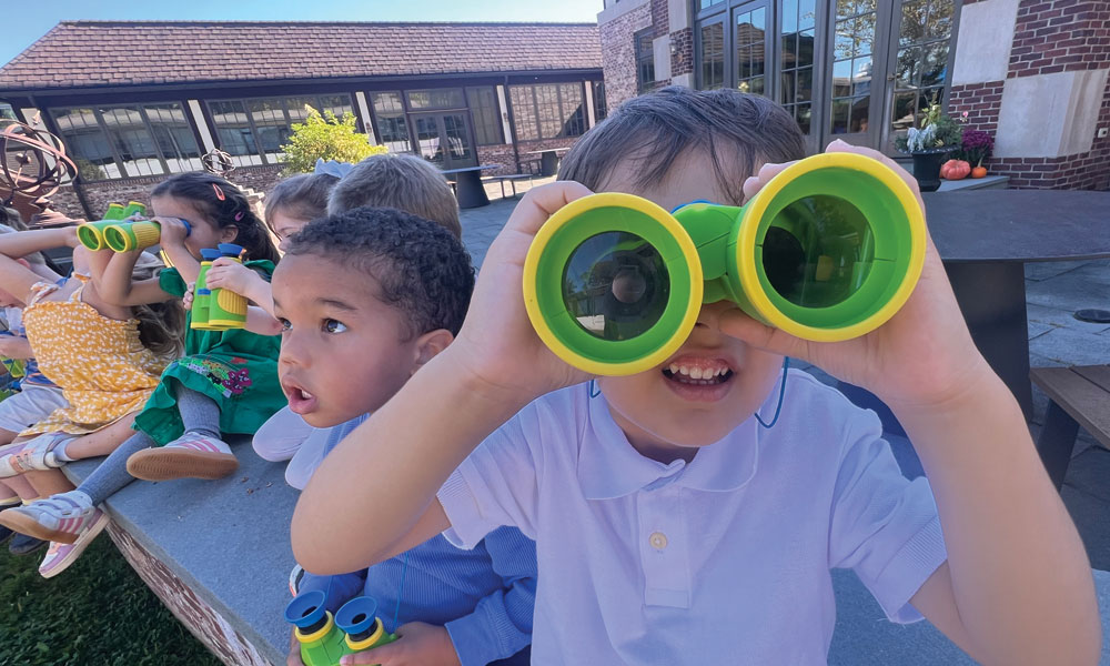 preschool students looking through binoculars