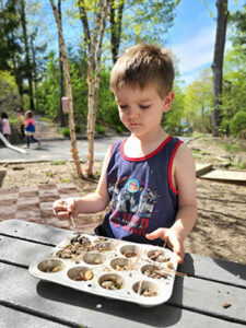 preschoool boy engaged in imaginative play at Renbrook School in the outdoor mud kitchen
