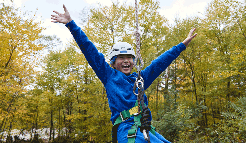 asian boy swinging through the air on Renbrook School's High ROPES Challenge Course