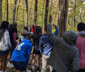 group of students with forester examining Renbrook's forest