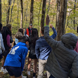 group of students with forester examining Renbrook's forest