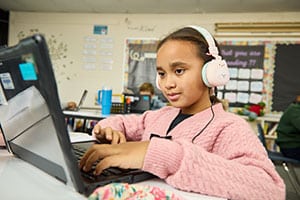 young african american girl in pink sweater working on computer