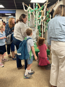 Several mothers with their young children looking at a Cardboard Challenge project built by Beginning School students and their teachers.