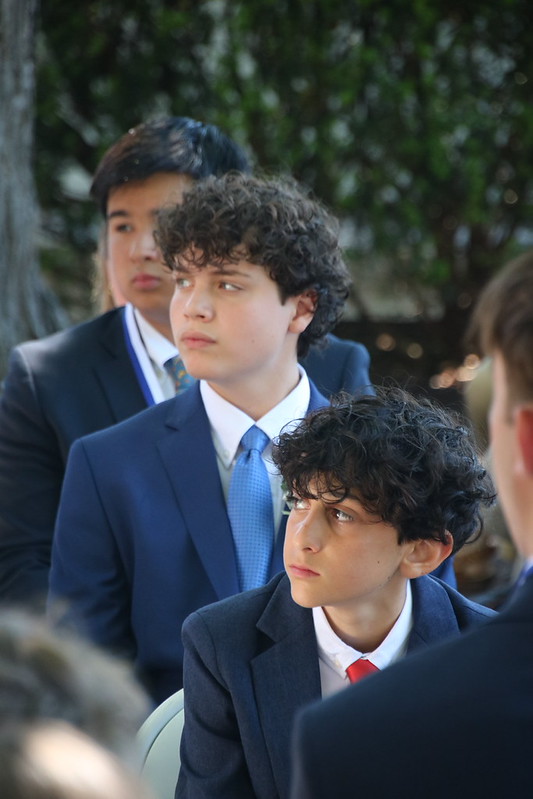 3 young men listening to graduation speaker