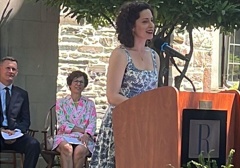 woman with curly hair standing at podium speaking