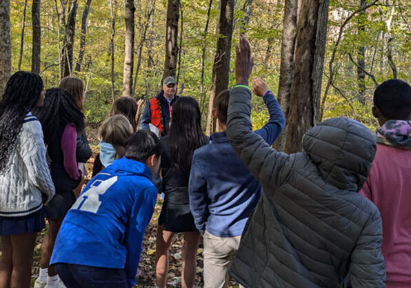 group of students with forester examining Renbrook's forest